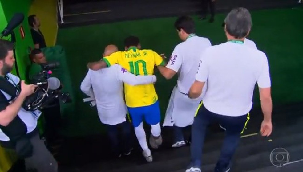 Neymar deixa o campo amparado, com gelo no tornozelo direito